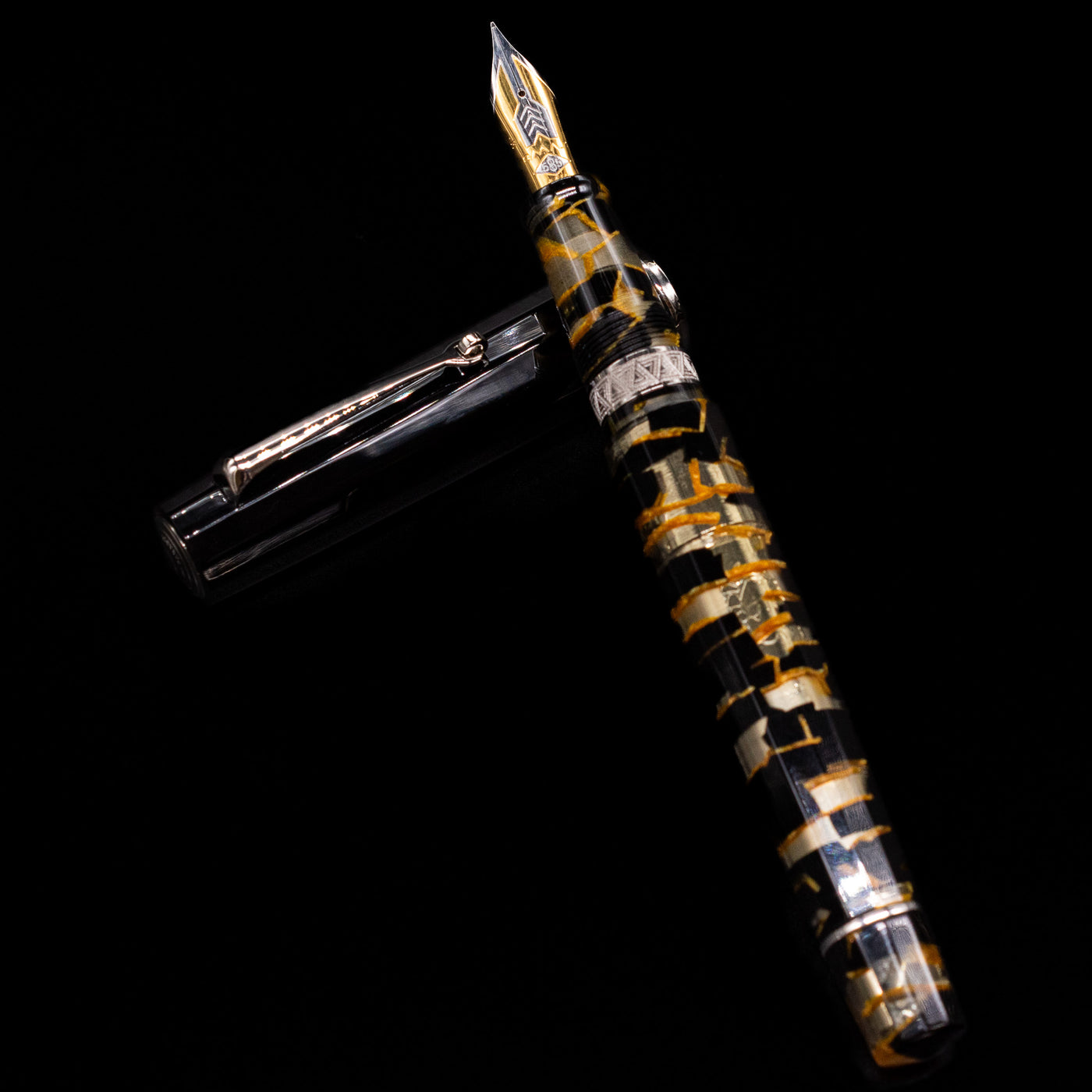 OMAS Paragon Fountain Pen - Black Lucen laying on top of its cap in a crossed position showing full view of the entire uncapped pen.