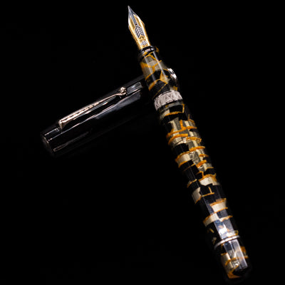 OMAS Paragon Fountain Pen - Black Lucen laying on top of its cap in a crossed position showing full view of the entire uncapped pen.