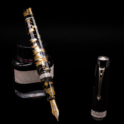 OMAS Paragon Fountain Pen - Black Lucen leaning on an ink bottle uncapped showcasing the detailing on the nib.
