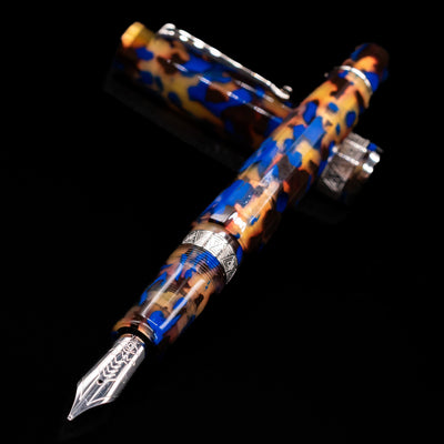 OMAS Paragon Fountain Pen - Blue Lucen laying across its own cap, crossed, with a focus on the nib.