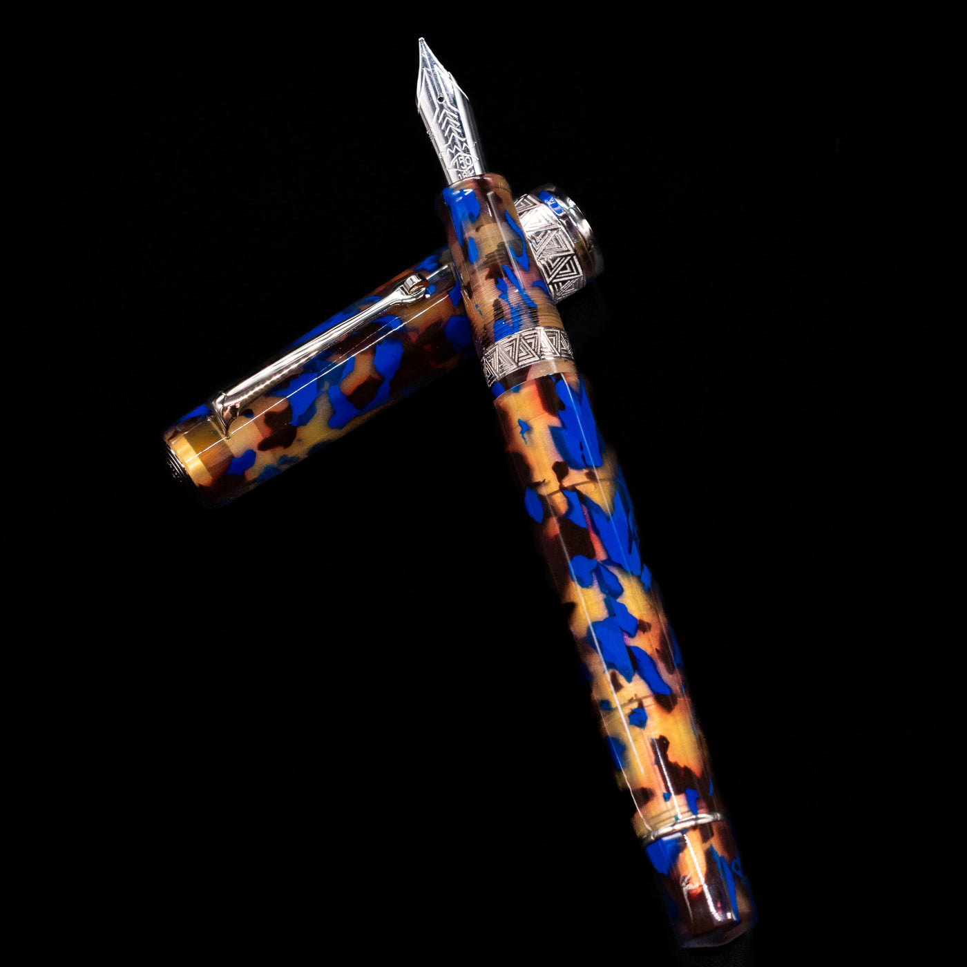 OMAS Paragon Fountain Pen - Blue Lucen laying on top of its cap in a crossed position showing full view of the entire uncapped pen.