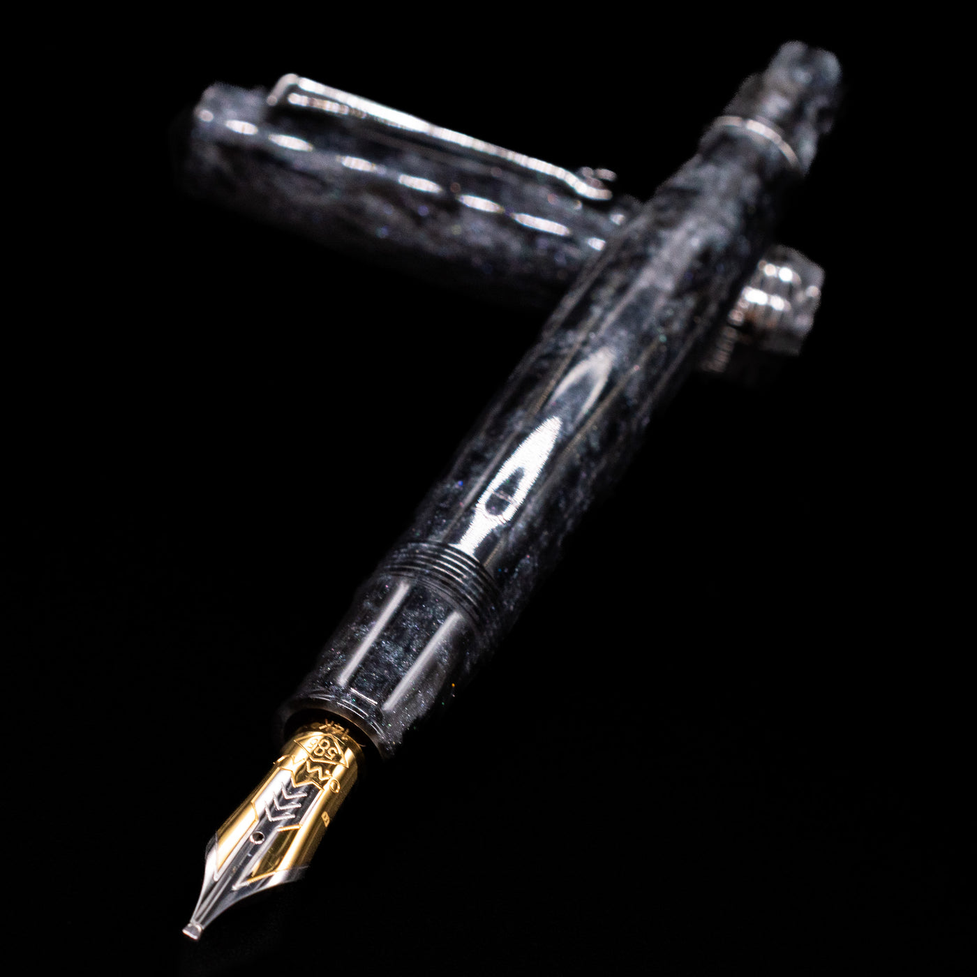 Omas Bologna Fountain Pen - Bright Grey laying across its own cap, crossed, with a focus on the nib.