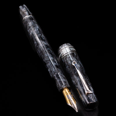 A full view of the Omas Bologna Fountain Pen - Bright Grey uncapped, with its cap laying next to the pen. 