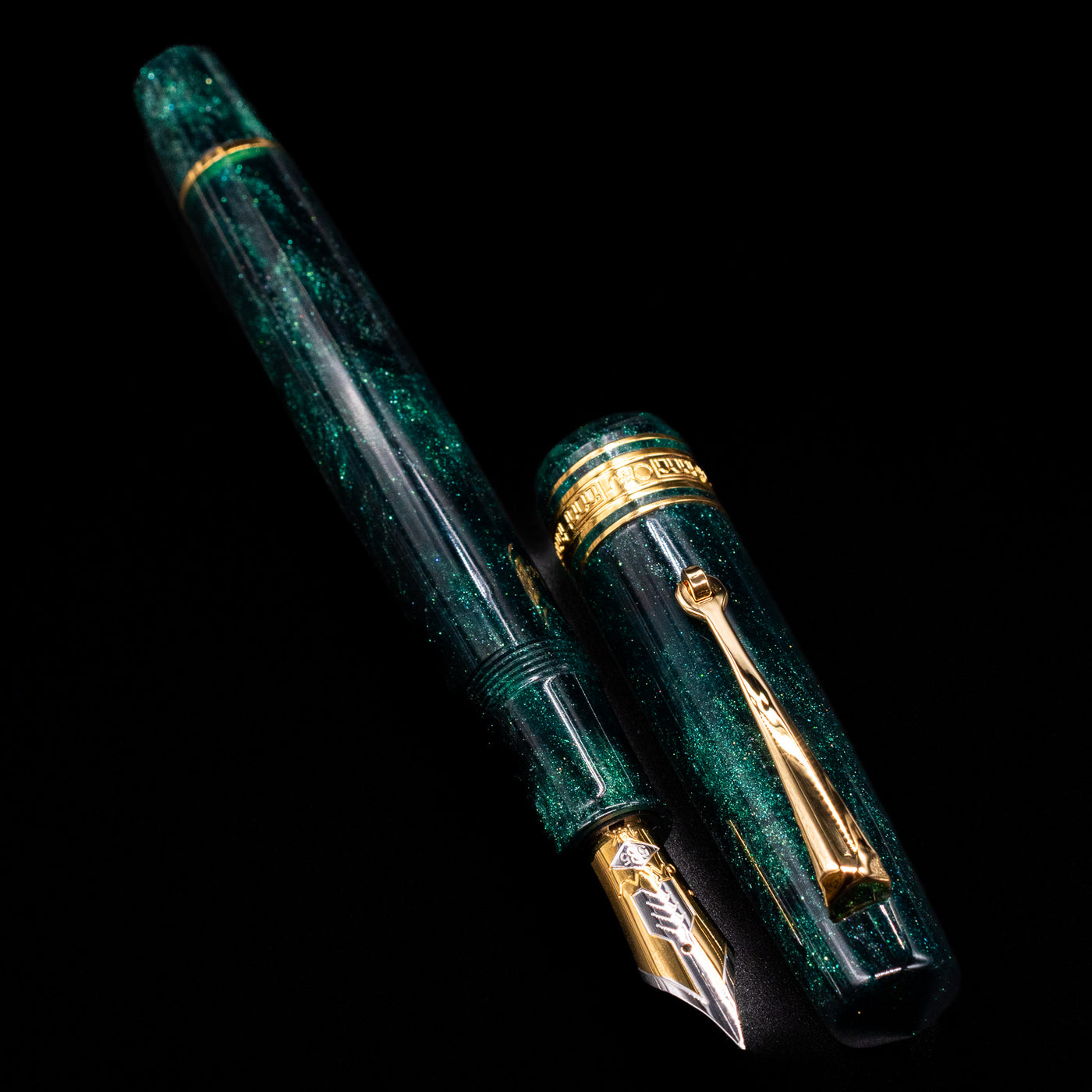 A full view of the Omas Bologna Fountain Pen - Elegant Emerald uncapped, with its cap laying next to the pen. 