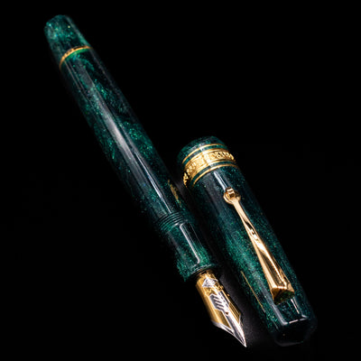 A full view of the Omas Bologna Fountain Pen - Elegant Emerald uncapped, with its cap laying next to the pen. 