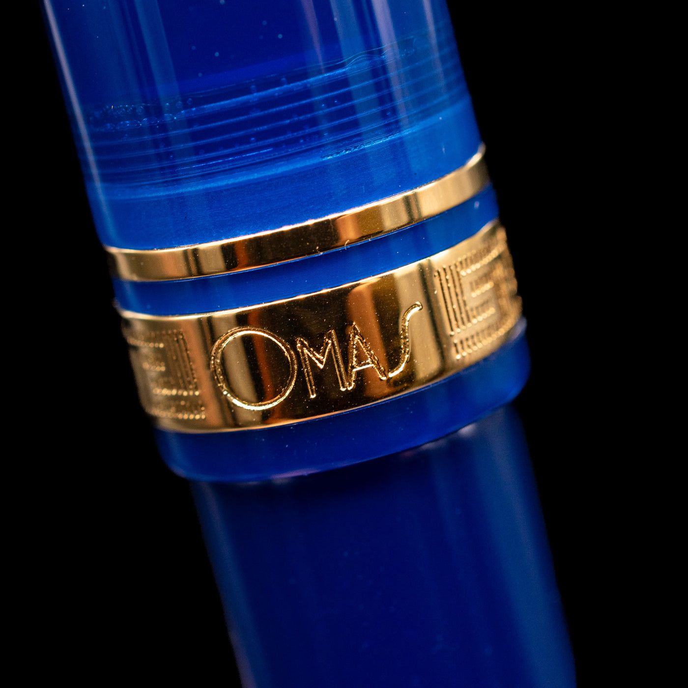 A macro shot of the center band with the Omas logo on the capped, leaning against an ink bottle. 