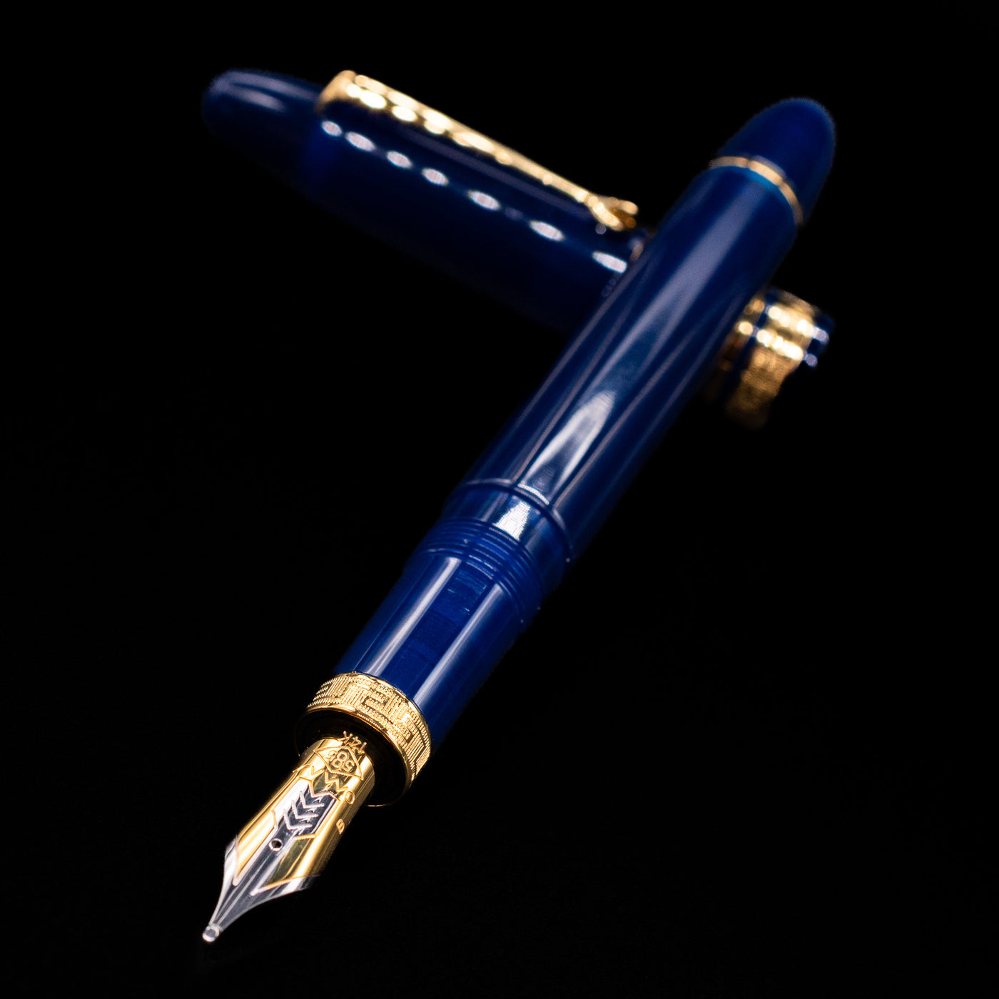 Omas Ogiva Fountain Pen - Blue Gold laying across its own cap, crossed, with a focus on the nib.