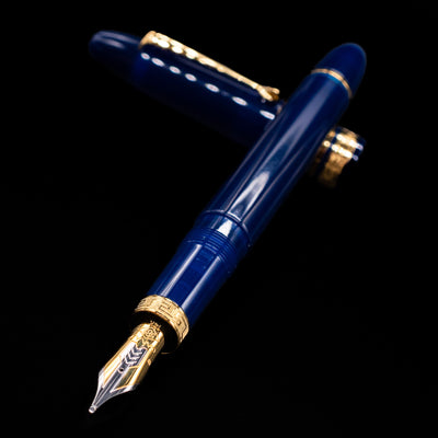 Omas Ogiva Fountain Pen - Blue Gold laying across its own cap, crossed, with a focus on the nib.