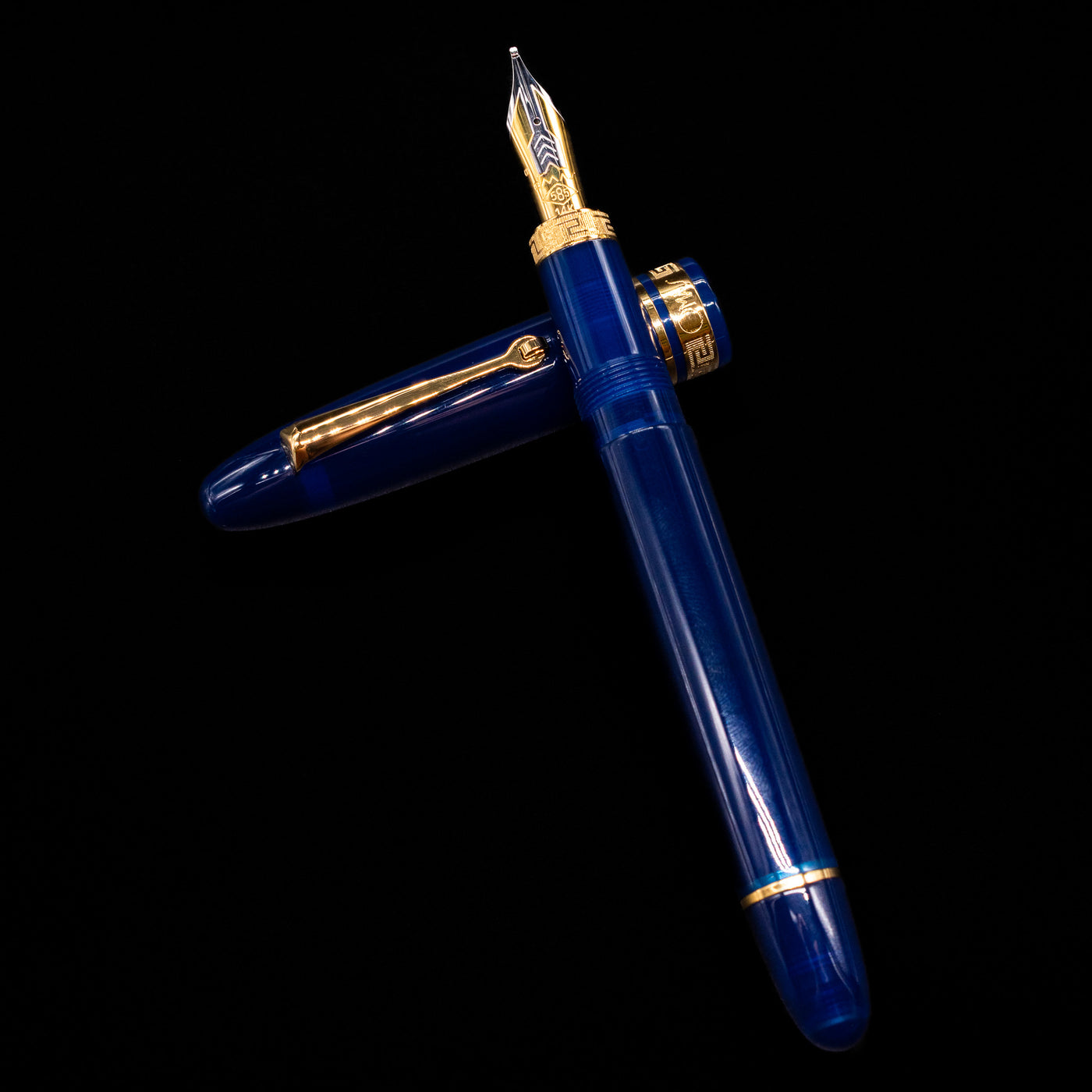 Omas Ogiva Fountain Pen - Blue Gold laying on top of its cap in a crossed position showing full view of the entire uncapped pen.