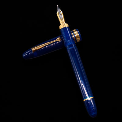 Omas Ogiva Fountain Pen - Blue Gold laying on top of its cap in a crossed position showing full view of the entire uncapped pen.