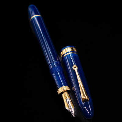 A full view of the Omas Ogiva Fountain Pen - Blue Gold uncapped, with its cap laying next to the pen. 
