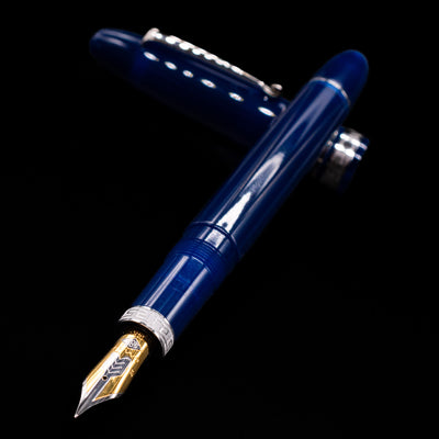 Omas Ogiva Fountain Pen - Blue Silver laying across its own cap, crossed, with a focus on the nib.