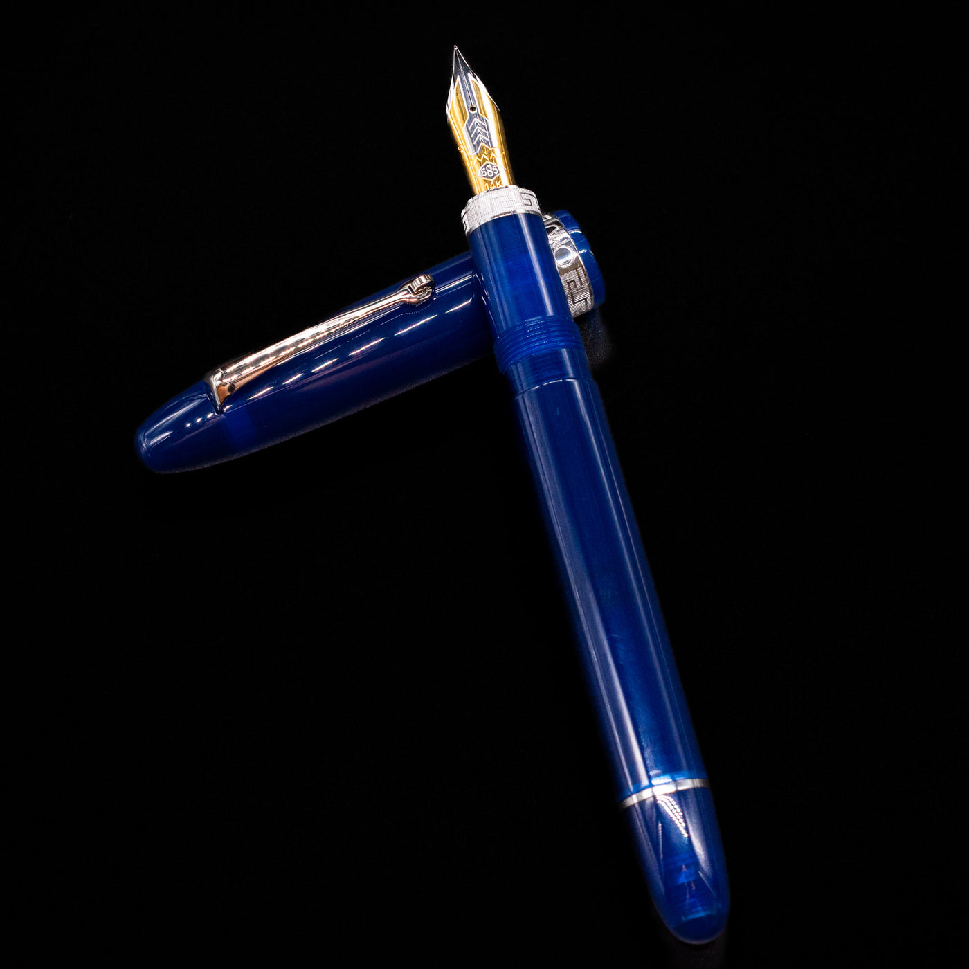 Omas Ogiva Fountain Pen - Blue Silver laying on top of its cap in a crossed position showing full view of the entire uncapped pen.
