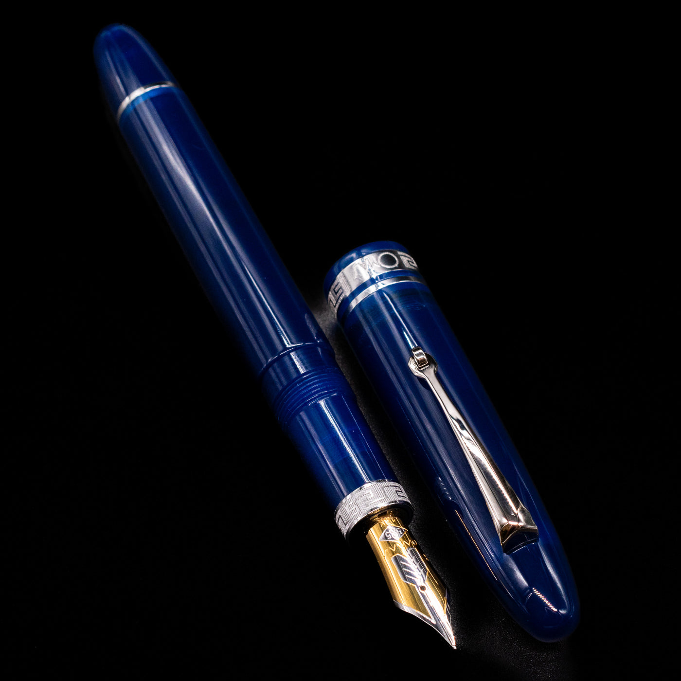 A full view of the Omas Ogiva Fountain Pen - Blue Silver uncapped, with its cap laying next to the pen. 