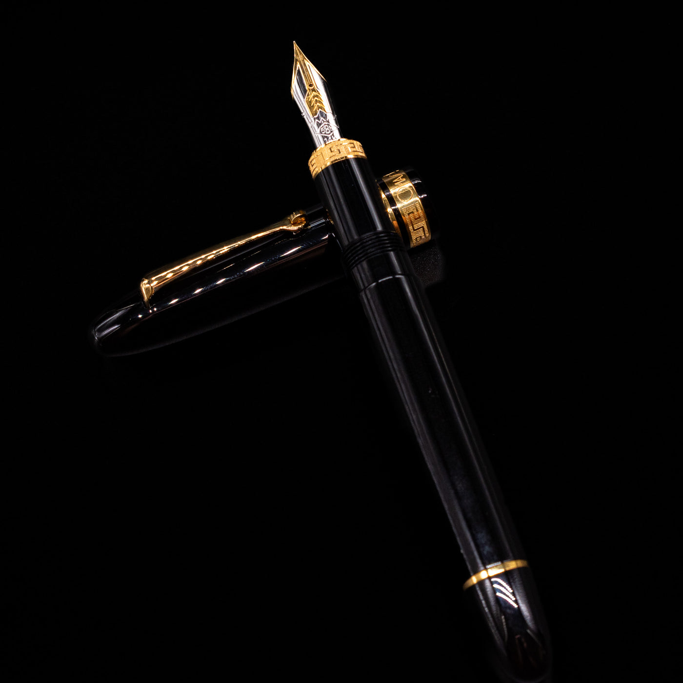 Omas Ogiva Fountain Pen - Nera Gold laying on top of its cap in a crossed position showing full view of the entire uncapped pen.