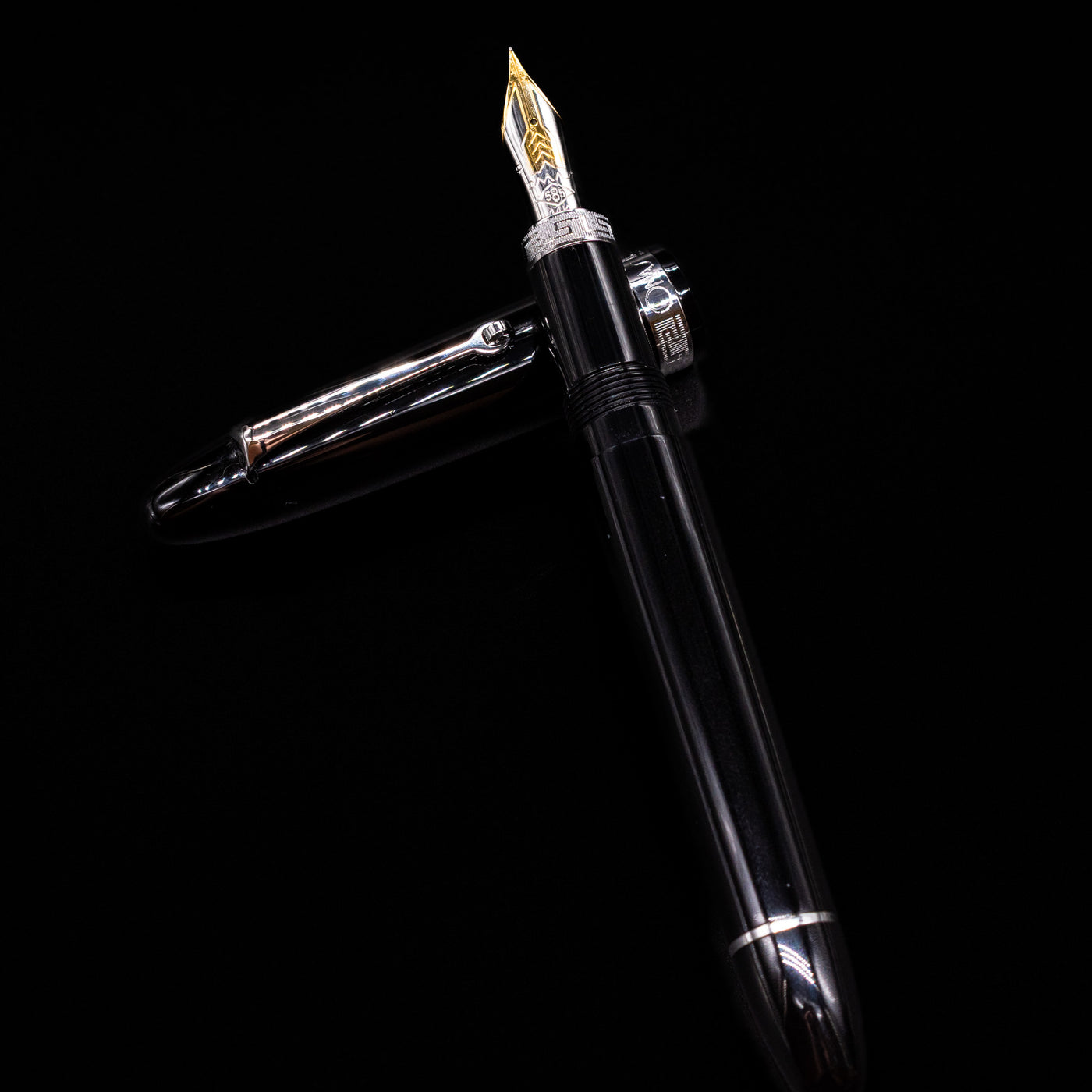 Omas Ogiva Fountain Pen - Nera Silver laying on top of its cap in a crossed position showing full view of the entire uncapped pen.