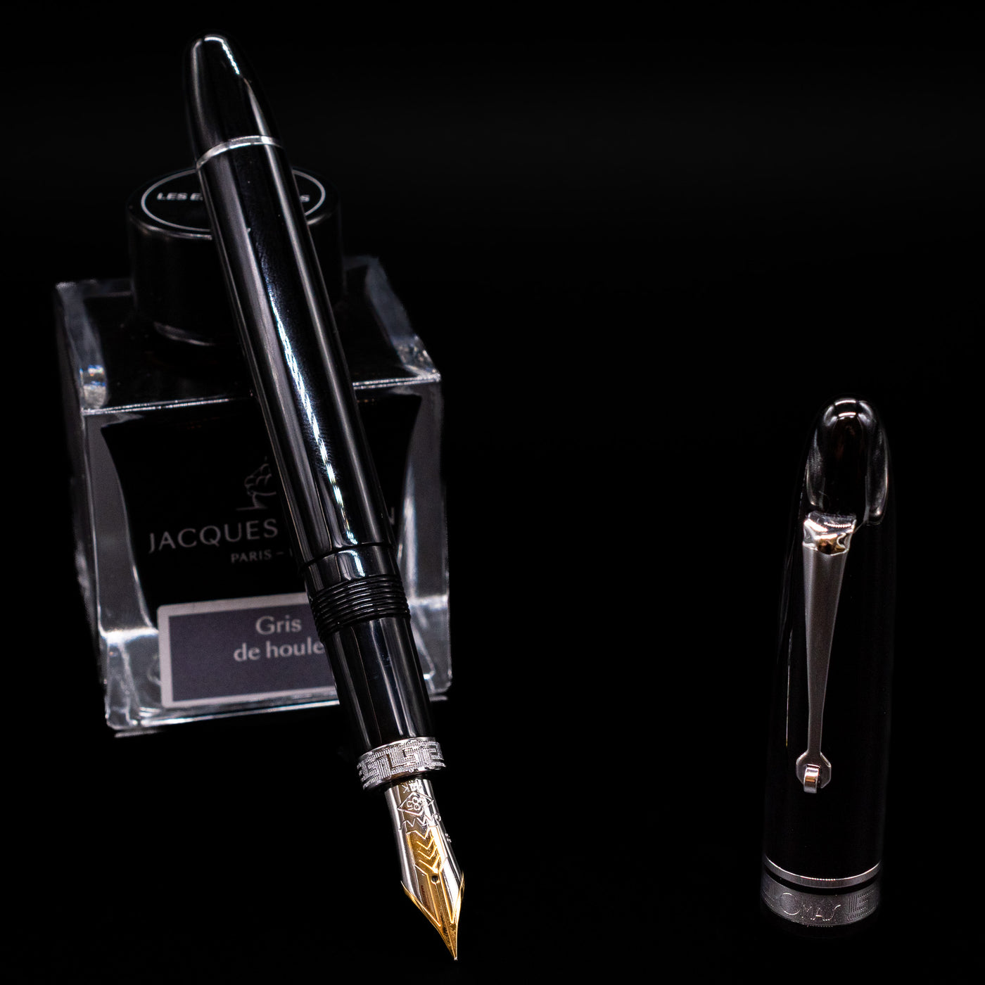 Omas Ogiva Fountain Pen - Nera Silver leaning on an ink bottle uncapped showcasing the detailing on the nib.