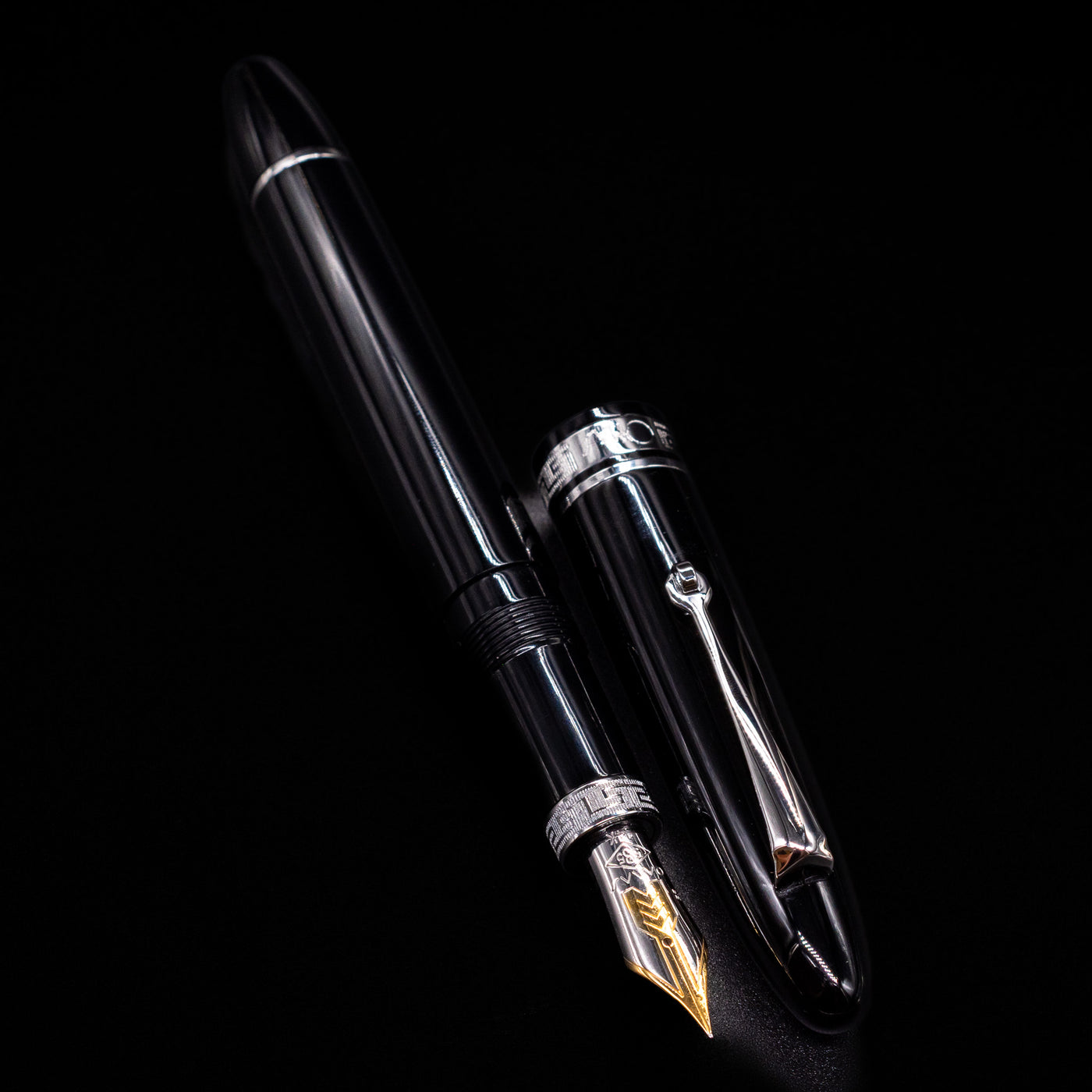 A full view of the Omas Ogiva Fountain Pen - Nera Silver uncapped, with its cap laying next to the pen.