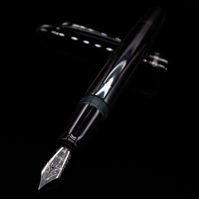 Opus 88 Jazz Solid Black Fountain Pen - Preowned laying across its own cap, crossed, with a focus on the nib.