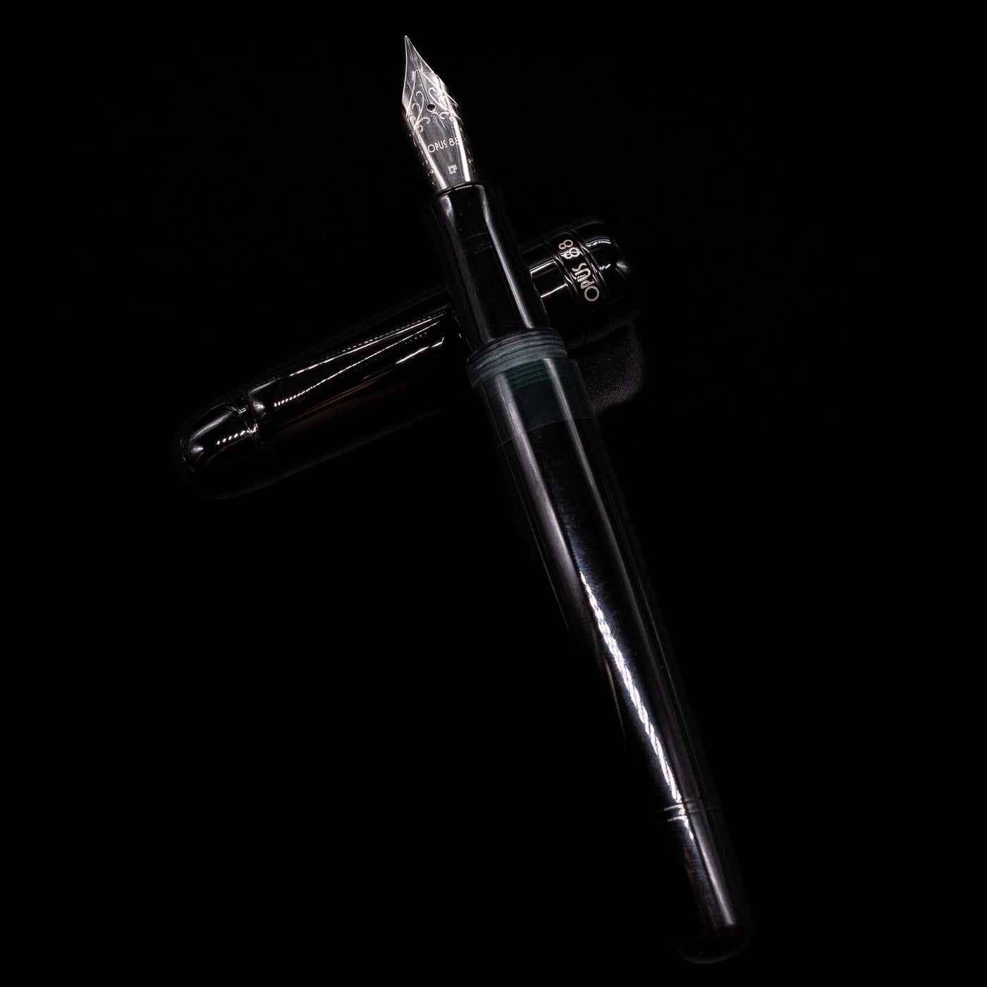 Opus 88 Jazz Solid Black Fountain Pen - Preowned laying on top of its cap in a crossed position showing full view of the entire uncapped pen.