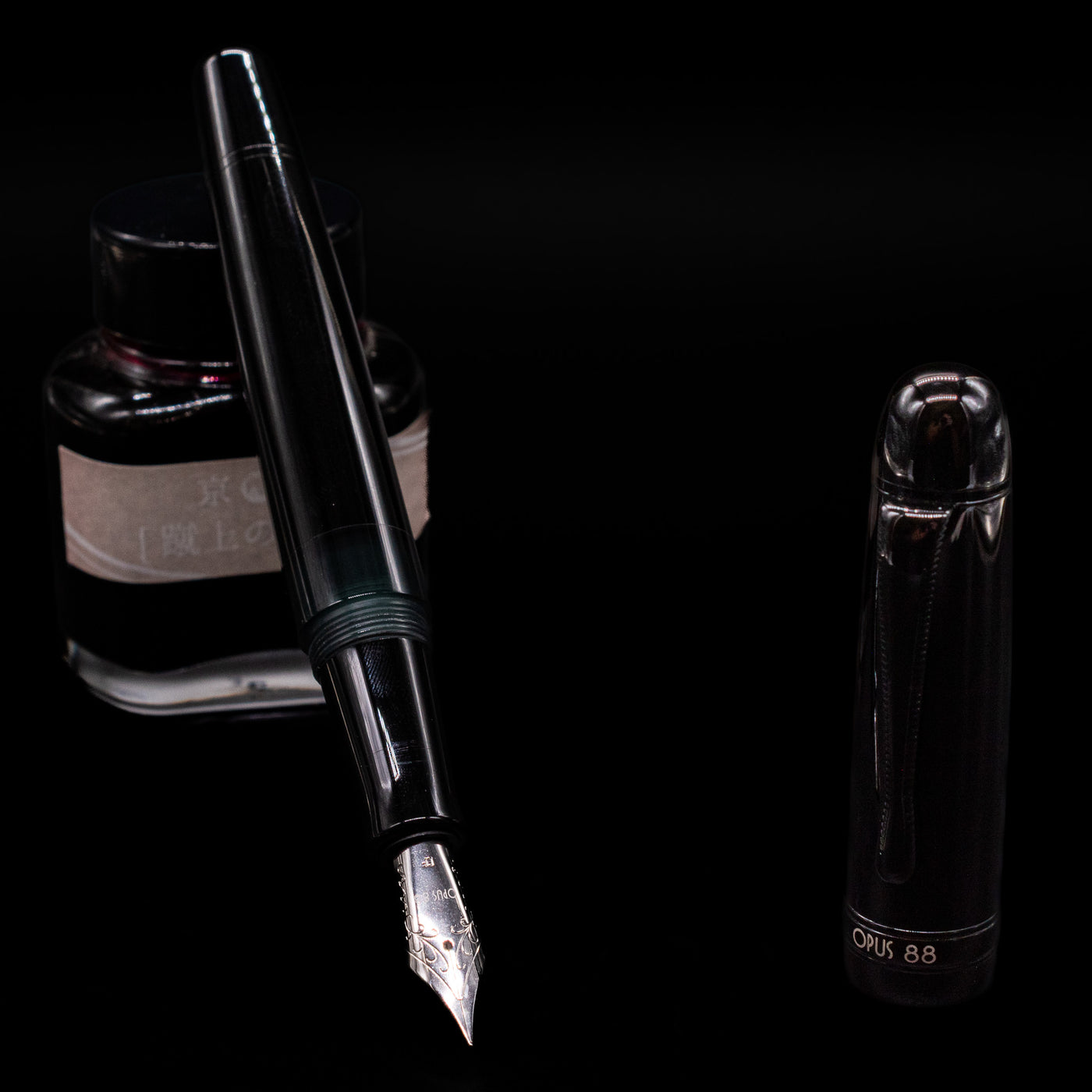 Opus 88 Jazz Solid Black Fountain Pen - Preowned leaning on an ink bottle uncapped showcasing the detailing on the nib.
