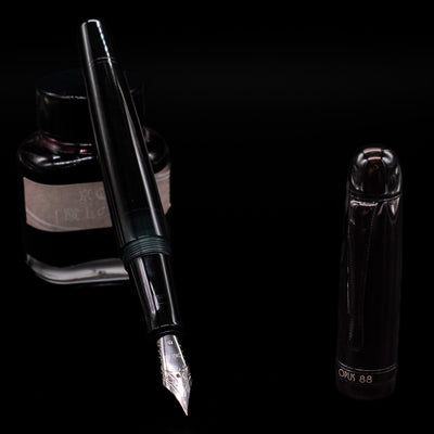 Opus 88 Jazz Solid Black Fountain Pen - Preowned leaning on an ink bottle uncapped showcasing the detailing on the nib.