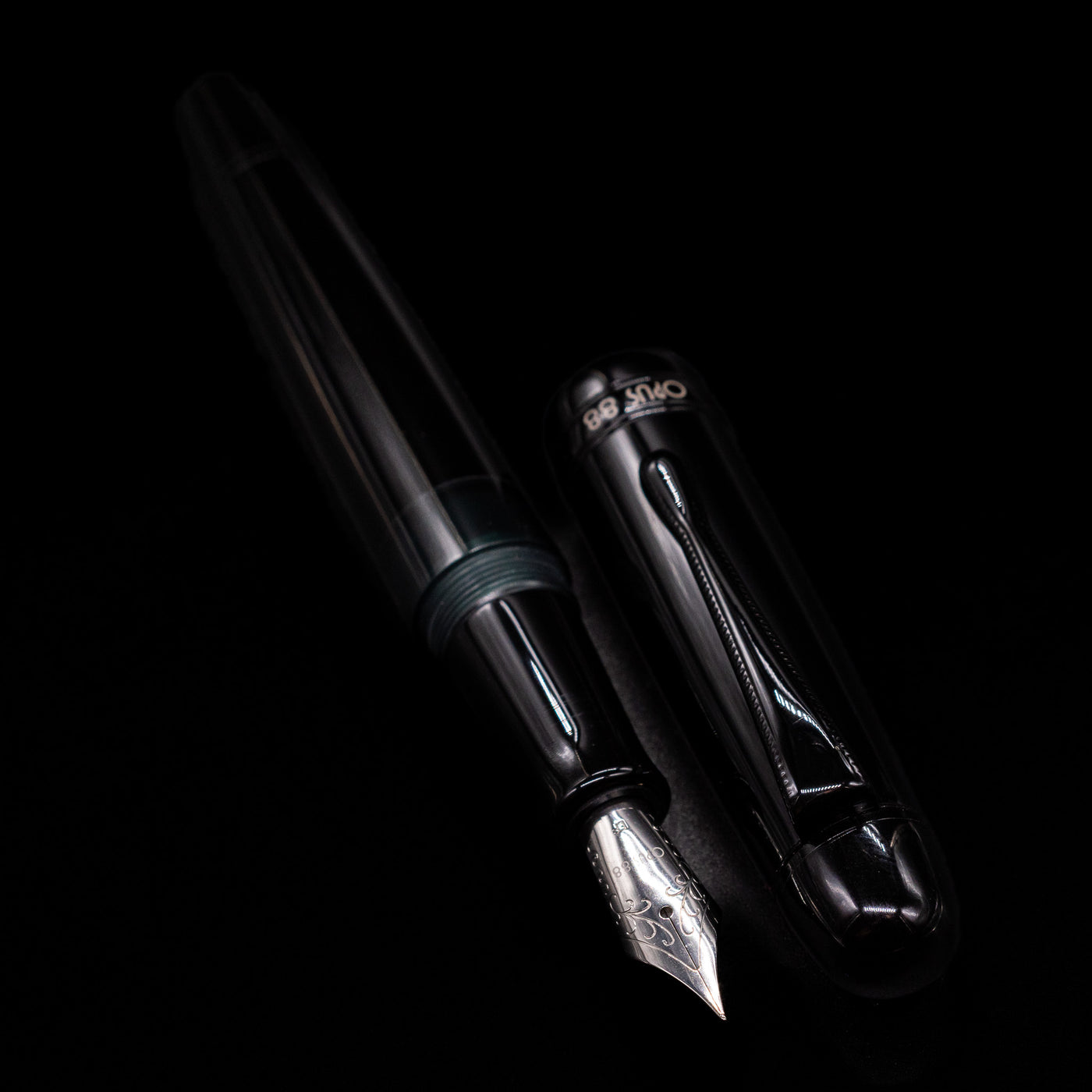 A full view of the Opus 88 Jazz Solid Black Fountain Pen - Preowned uncapped, with its cap laying next to the pen. 