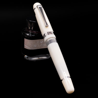 Opus 88 Jazz Solid White Fountain Pen - Preowned capped, leaning against an ink bottle. 