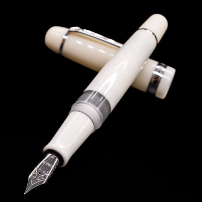 Opus 88 Jazz Solid White Fountain Pen - Preowned laying across its own cap, crossed, with a focus on the nib.