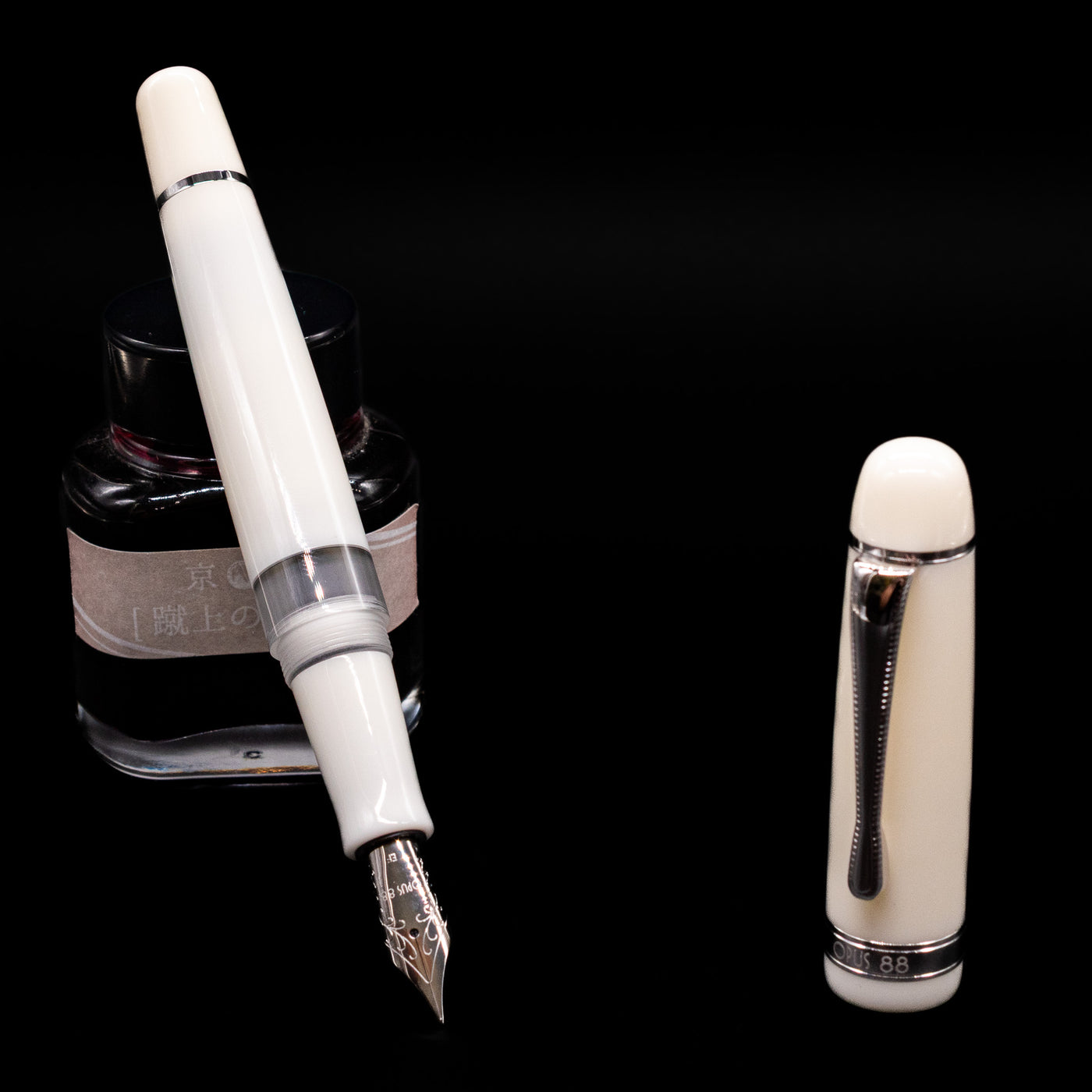 Opus 88 Jazz Solid White Fountain Pen - Preowned leaning on an ink bottle uncapped showcasing the detailing on the nib.