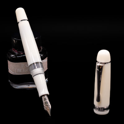 Opus 88 Jazz Solid White Fountain Pen - Preowned leaning on an ink bottle uncapped showcasing the detailing on the nib.