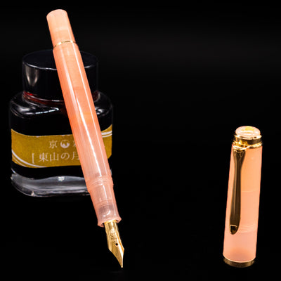 Pelikan Classic M200 Fountain Pen - Apricot Achat leaning on an ink bottle uncapped showcasing the detailing on the nib.