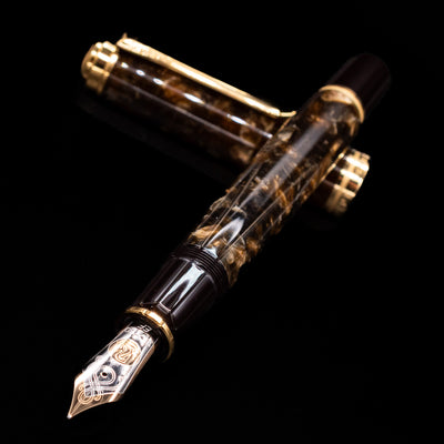 Pelikan Souverän M1000 Renaissance Brown fountain pen and cap crossed, with focus on the engraved 18k gold nib and the swirling marbled brown finish of the barrel.