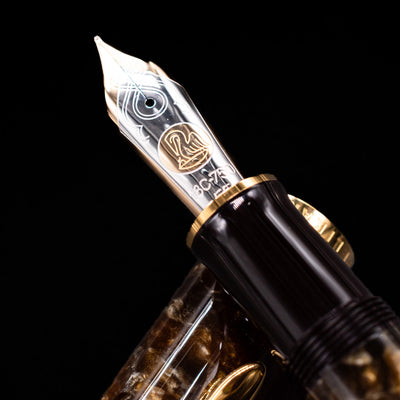 Close-up of the 18k bi-color gold nib on the Pelikan Souverän M1000 Renaissance Brown fountain pen, featuring elaborate scrollwork and the Pelikan logo.