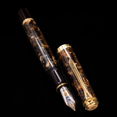 Pelikan Souverän M1000 Renaissance Brown fountain pen displayed uncapped, revealing the deep marbled brown barrel, glossy black grip section, and the oversized gold nib.