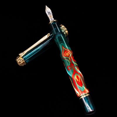 Pelikan Souveran M605 Art Collection Fountain Pen - Rudi Rother  laying on top of its cap in a crossed position showing full view of the entire uncapped pen.
