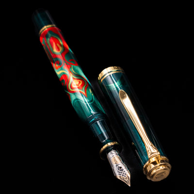 A full view of the Pelikan Souveran M605 Art Collection Fountain Pen - Rudi Rother uncapped, with its cap laying next to the pen. 