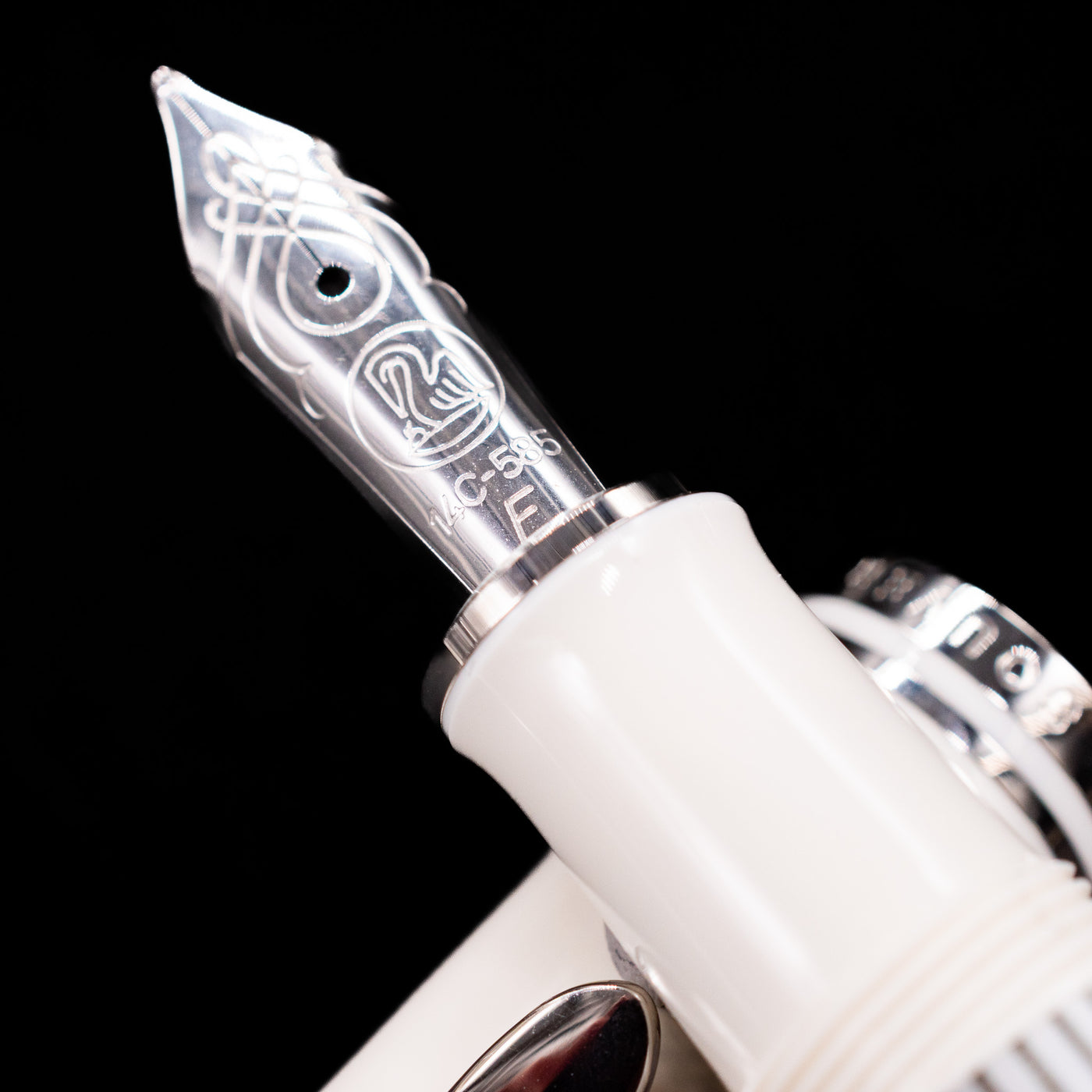 Close-up shot of the rhodium-plated 14k gold nib on the Pelikan Souverän M605 White Transparent fountain pen, showing detailed engravings and fine craftsmanship.