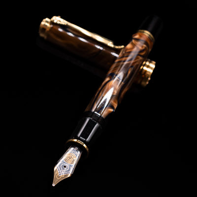 Pelikan Souveran M800 Fountain Pen - Grand Place laying across its own cap, crossed, with a focus on the nib.