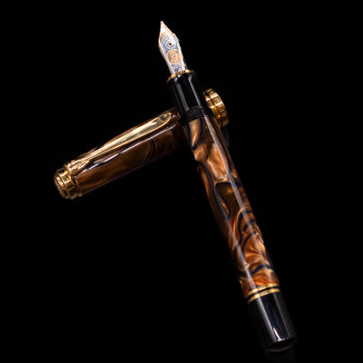 Pelikan Souveran M800 Fountain Pen - Grand Place laying on top of its cap in a crossed position showing full view of the entire uncapped pen.