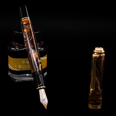 Pelikan Souveran M800 Fountain Pen - Grand Place leaning on an ink bottle uncapped showcasing the detailing on the nib.