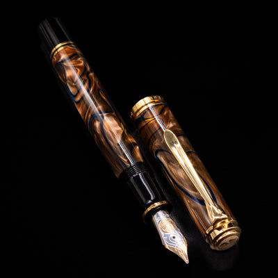  A full view of the Pelikan Souveran M800 Fountain Pen - Grand Place uncapped, with its cap laying next to the pen. 