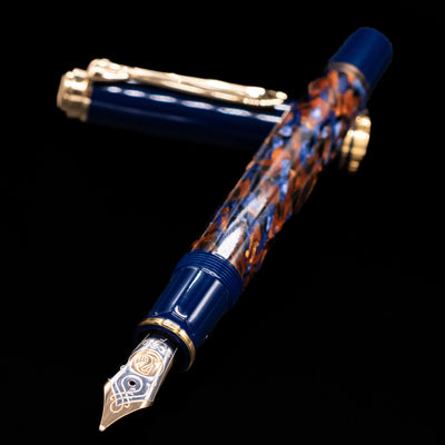 Preowned Pelikan Souverän M800 Stone Garden fountain pen and cap crossed, with focus on the engraved gold nib and the shimmering marbled blue barrel.