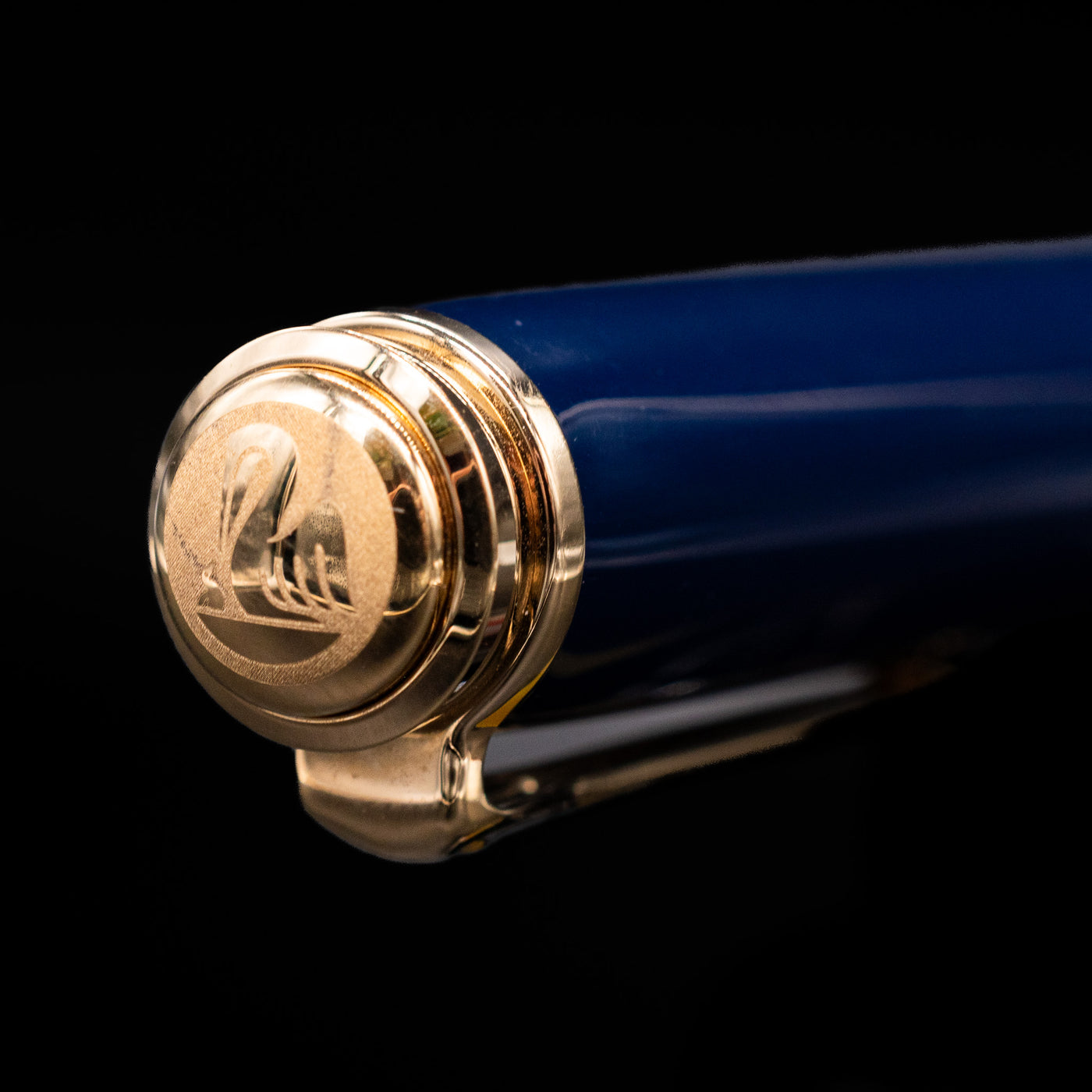 Close-up of the cap top on the preowned Pelikan Souverän M800 Stone Garden fountain pen, featuring the Pelikan logo medallion set into the glossy blue resin finial with gold trim.
