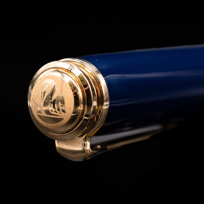 Close-up of the cap top on the preowned Pelikan Souverän M800 Stone Garden fountain pen, featuring the Pelikan logo medallion set into the glossy blue resin finial with gold trim.