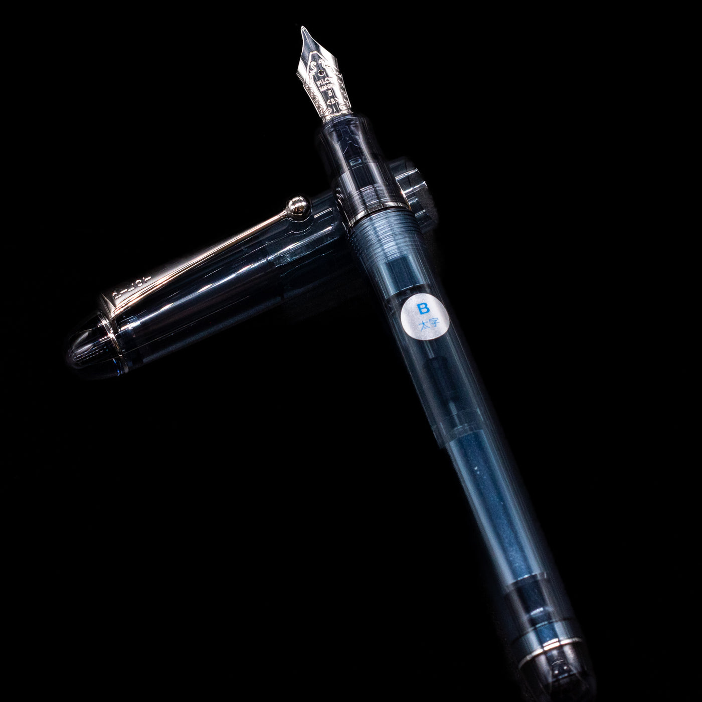 Pilot Custom 74 Fountain Pen - Blue Stone laying on top of its cap in a crossed position showing full view of the entire uncapped pen.