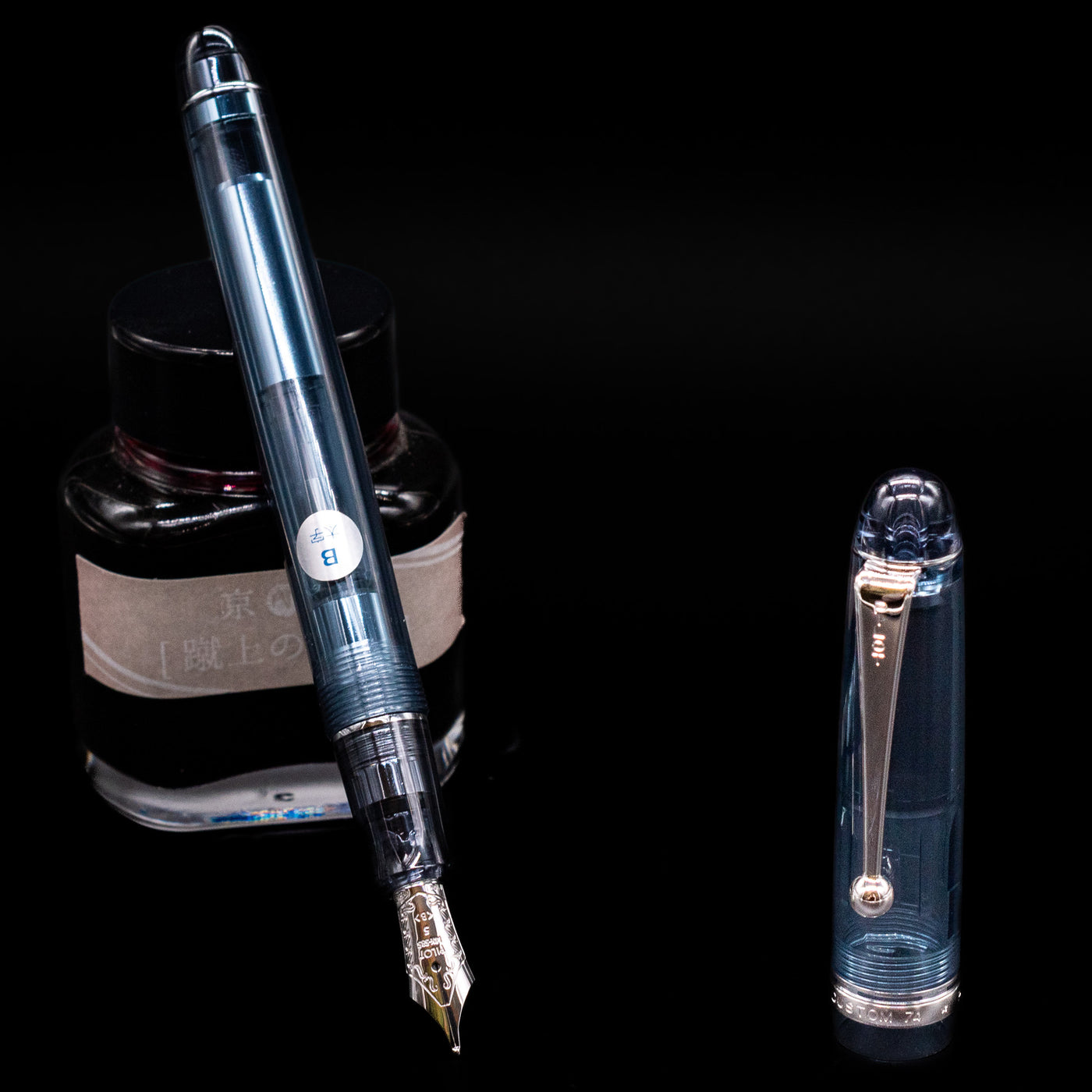 Pilot Custom 74 Fountain Pen - Blue Stone leaning on an ink bottle uncapped showcasing the detailing on the nib.