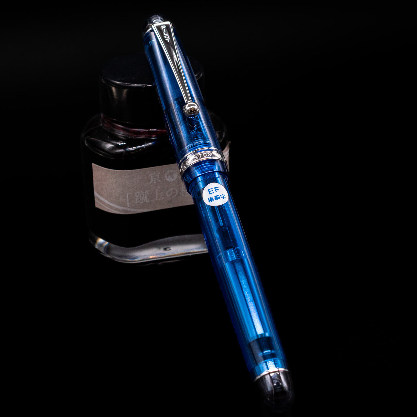 Pilot Custom 74 Fountain Pen - Blue capped, leaning against an ink bottle. 