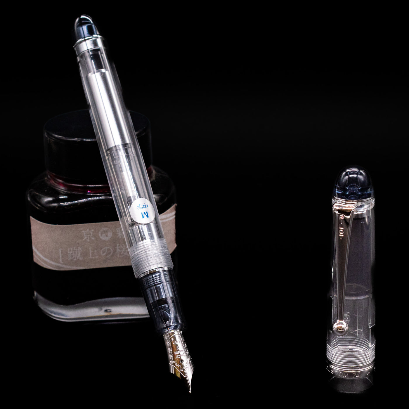 Pilot Custom 74 Fountain Pen - Clear leaning on an ink bottle uncapped showcasing the detailing on the nib.