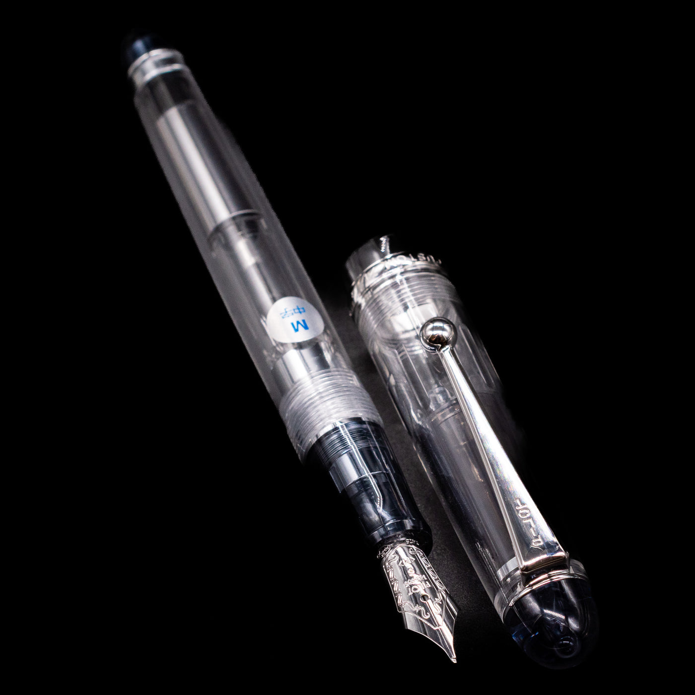 A full view of the Pilot Custom 74 Fountain Pen - Clear uncapped, with its cap laying next to the pen. 